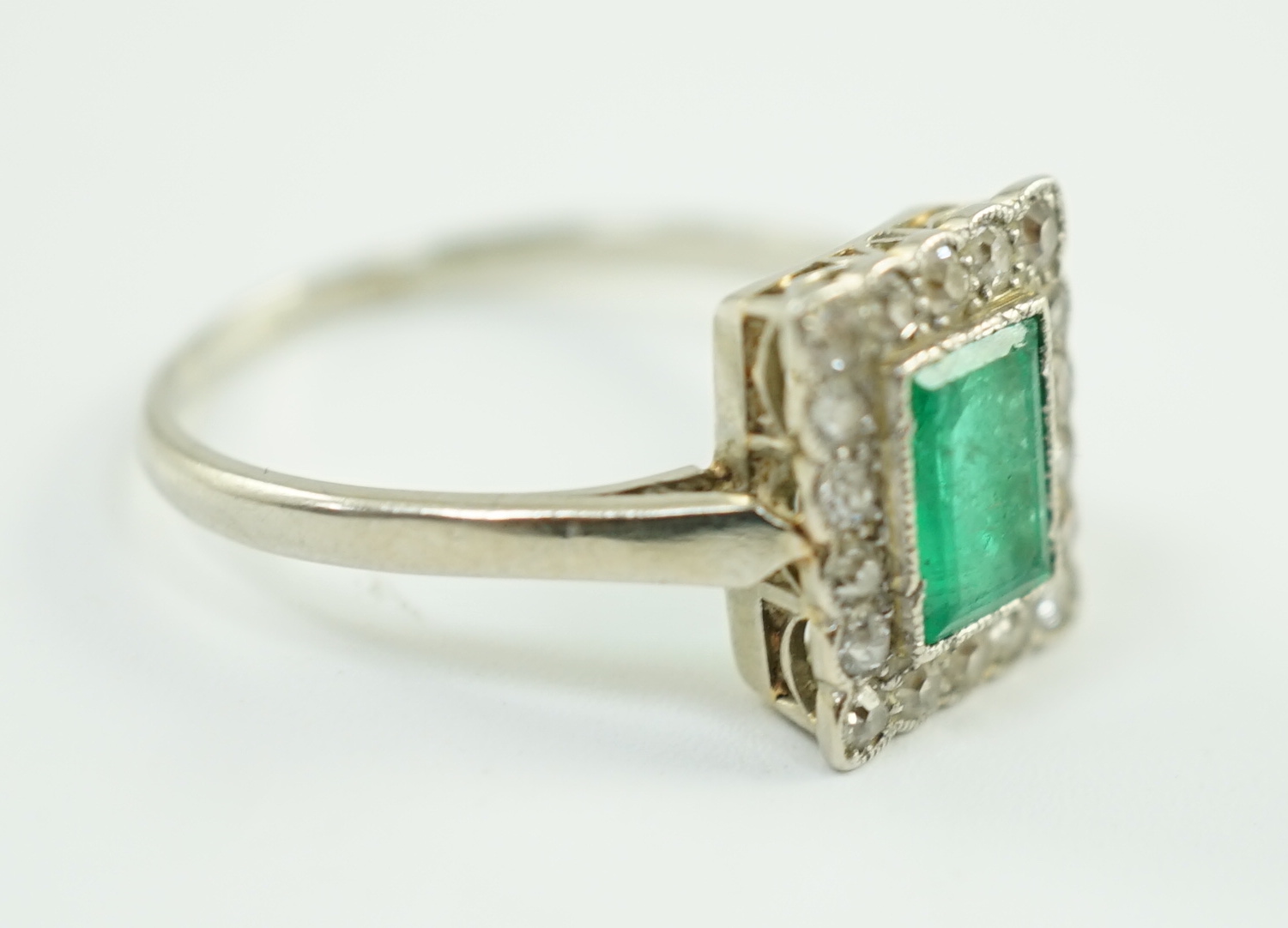 A 1920's 18ct white gold and platinum, emerald and millegrain set diamond rectangular cluster ring